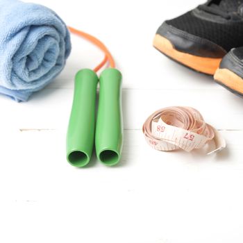 fitness equipment : running shoes,towel,jumping rope and measuring tape on white wood table
