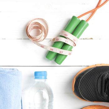 fitness equipment : running shoes,towel,jumping rope,water bottle and measuring tape on white wood table