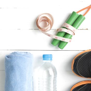 fitness equipment : running shoes,towel,jumping rope,water bottle and measuring tape on white wood table