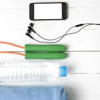 fitness equipment :towel,jumping rope,water bottle and phone on white wood table