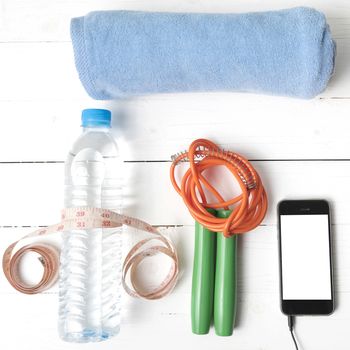 fitness equipment :towel,jumping rope,water bottle,phone and measuring tape on white wood table