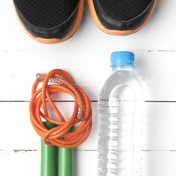 fitness equipment : running shoes,jumping rope and water bottle on white wood table