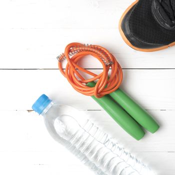 fitness equipment : running shoes,jumping rope and water bottle on white wood table