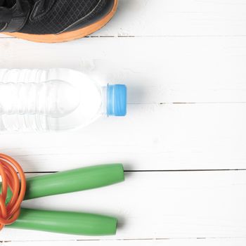 fitness equipment : running shoes,jumping rope and water bottle on white wood table