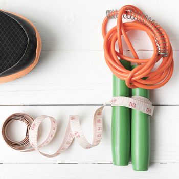 fitness equipment : running shoes,jumping rope and measuring tape on white wood table