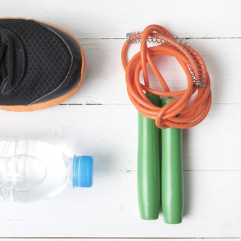 fitness equipment : running shoes,jumping rope and water bottle on white wood table