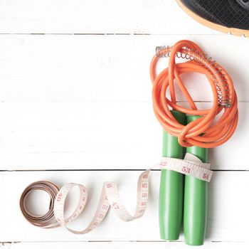 fitness equipment : running shoes,jumping rope and measuring tape on white wood table