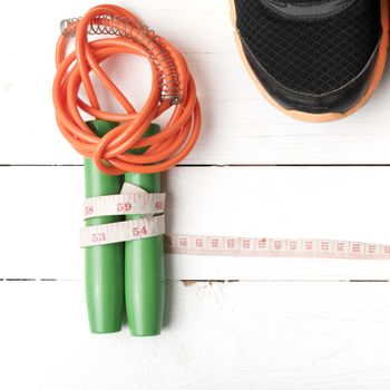 fitness equipment : running shoes,jumping rope and measuring tape on white wood table