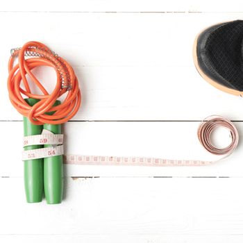 fitness equipment : running shoes,jumping rope and measuring tape on white wood table