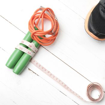 fitness equipment : running shoes,jumping rope and measuring tape on white wood table