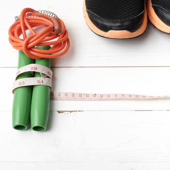 fitness equipment : running shoes,jumping rope and measuring tape on white wood table