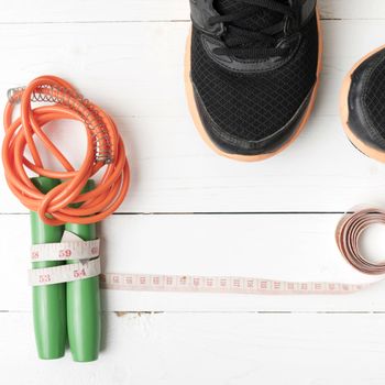 fitness equipment : running shoes,jumping rope and measuring tape on white wood table