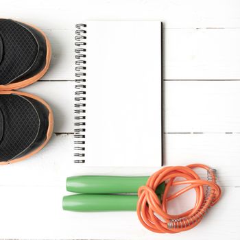 fitness equipment : running shoes,jumping rope and notepad on white wood table