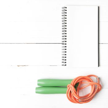 fitness equipment : jumping rope and notepad on white wood table