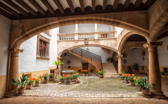 Picturesque mediterranean courtyard with stone pillars and flowers, Palma de Mallorca, Spain