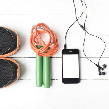fitness equipment : running shoes,jumping rope and phone on white wood table