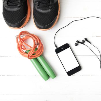 fitness equipment : running shoes,jumping rope and phone on white wood table