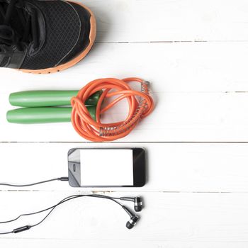 fitness equipment : running shoes,jumping rope and phone on white wood table