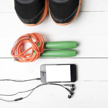 fitness equipment : running shoes,jumping rope and phone on white wood table