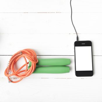 fitness equipment : jumping rope and phone on white wood table