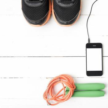 fitness equipment : running shoes,jumping rope and phone on white wood table