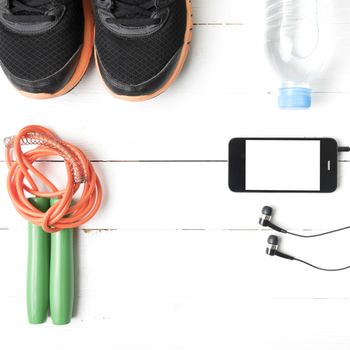 fitness equipment : running shoes,jumping rope,phone and water bottle on white wood table