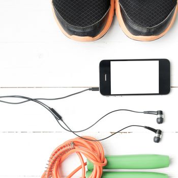 fitness equipment : running shoes,jumping rope and phone on white wood table