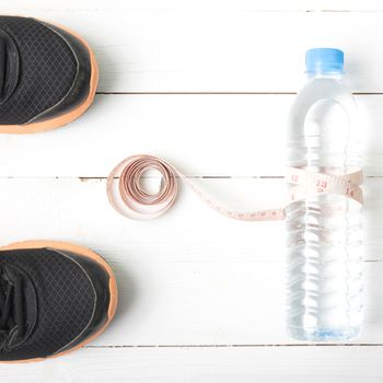 fitness equipment : running shoes,drinking water and measuring tape on white wood table