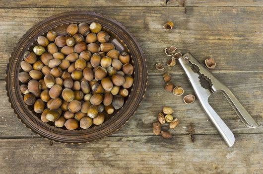 Hazelnuts and nutcracker in wooden background