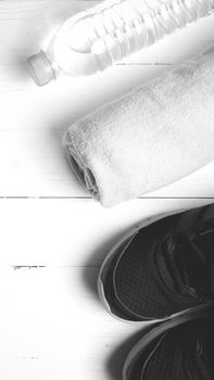 fitness equipment: towel,drinking water and running shoes on white wood table black and white color style