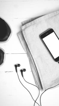 fitness equipment:running shoes,towel and smart phone on white wood table black and white color style