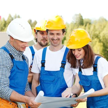 Team of happy smiling workers look at construction blueprint