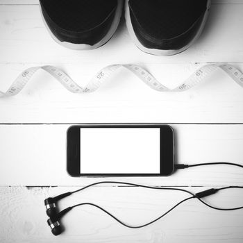 running shoes,measuring tape and phone on white wood table black and white tone color style