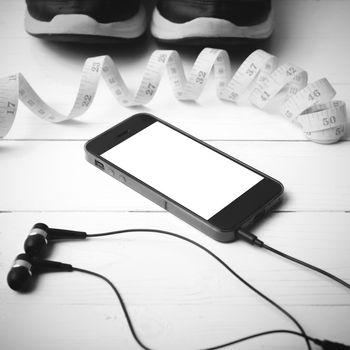 running shoes,measuring tape and phone on white wood table black and white tone color style