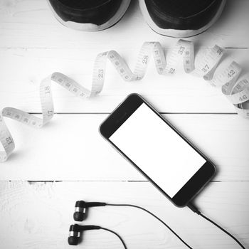 running shoes,measuring tape and phone on white wood table black and white tone color style