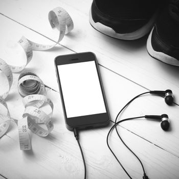 running shoes,measuring tape and phone on white wood table black and white tone color style