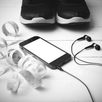 running shoes,measuring tape and phone on white wood table black and white tone color style