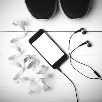 running shoes,measuring tape and phone on white wood table black and white tone color style