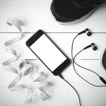 running shoes,measuring tape and phone on white wood table black and white tone color style