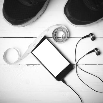 running shoes,measuring tape and phone on white wood table black and white tone color style