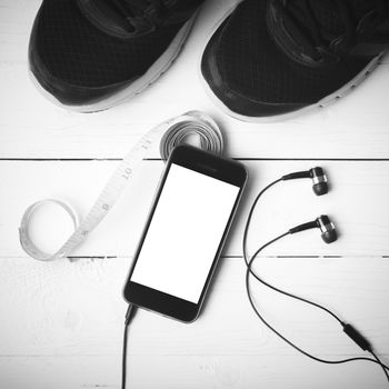 running shoes,measuring tape and phone on white wood table black and white tone color style
