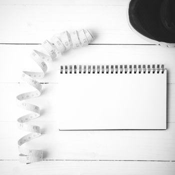 running shoes with notebook and measuring tape on white wood table black and white tone color style