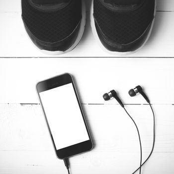 running shoes and phone on white wood table black and white tone color style
