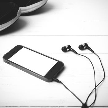 running shoes and phone on white wood table black and white tone color style