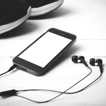 running shoes and phone on white wood table black and white tone color style