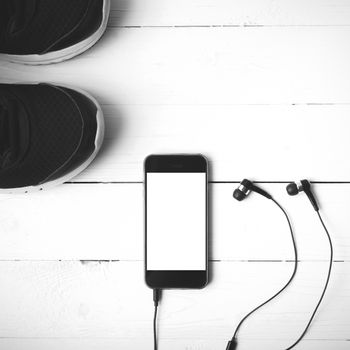 running shoes and phone on white wood table black and white tone color style