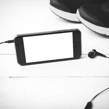 running shoes and phone on white wood table black and white tone color style