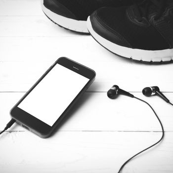 running shoes and phone on white wood table black and white tone color style