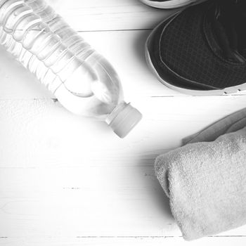 fitness equipment: towel,drinking water and running shoes on white wood table black and white color style