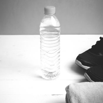 fitness equipment: towel,drinking water and running shoes on white wood table black and white color style